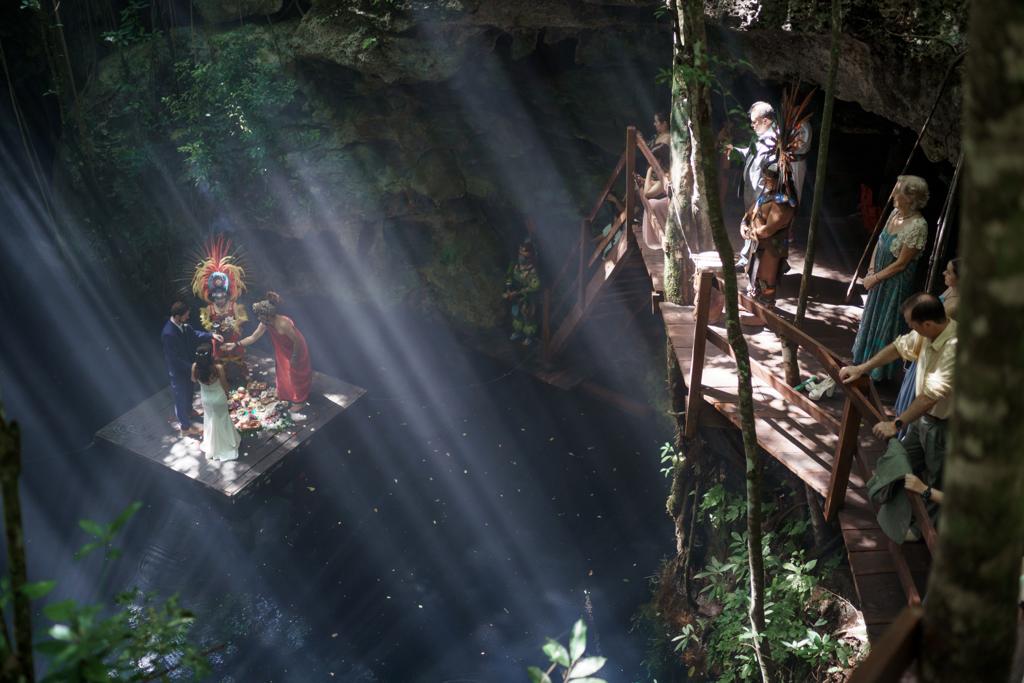 Una ceremonia maya en una plataforma dentro de un cenote, iluminada por un haz de sol