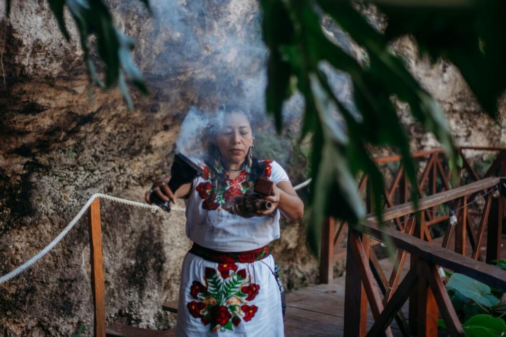 Mayan woman performing a sacred smoke cleansing ritual during a cenote wedding ceremony in Quintana Roo