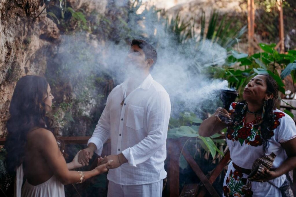 Couple participating in a traditional Mayan cleansing ritual with smoke during a cenote wedding ceremony in Mexico
