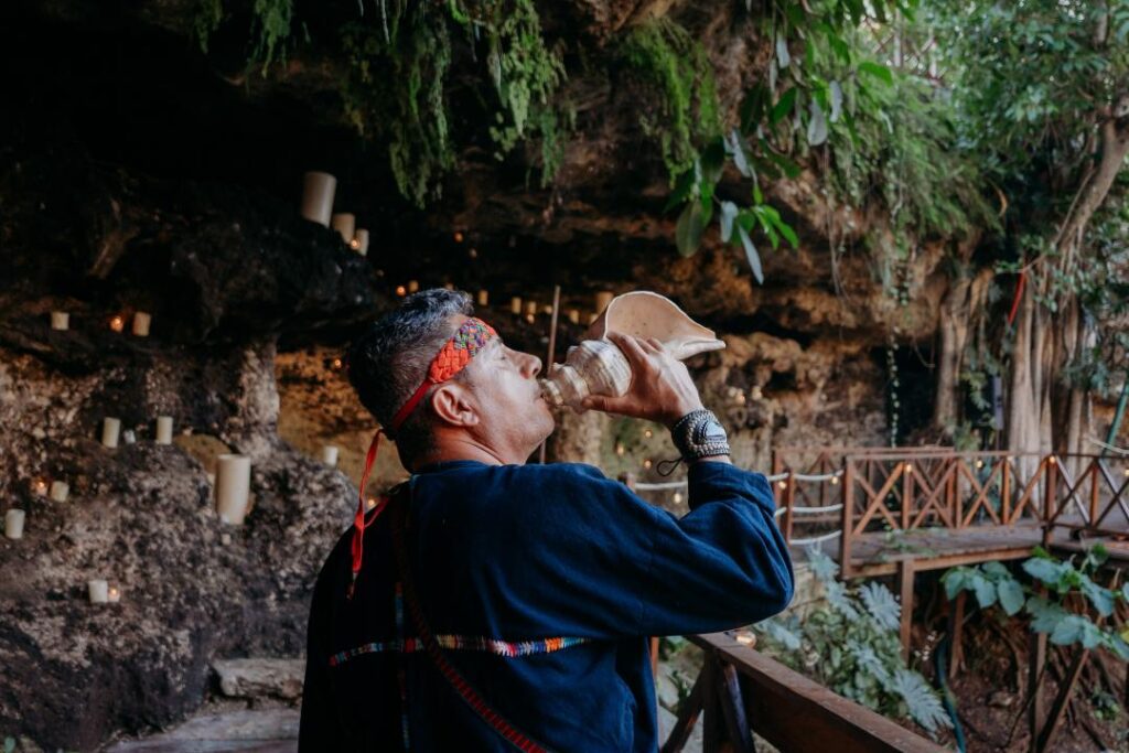 Mayan officiant using traditional instruments during a spiritual cenote wedding ritual in Mexico