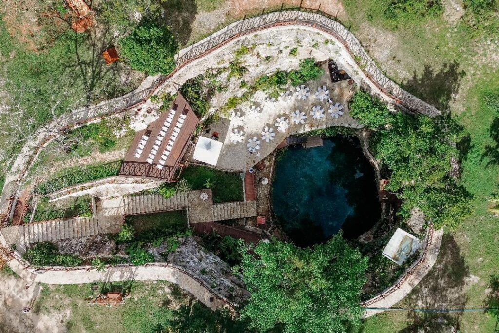 Drone view of a hidden cenote surrounded by jungle in Quintana Roo, ideal for destination weddings