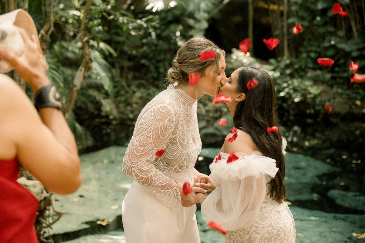 Two brides under falling petals in the jungle