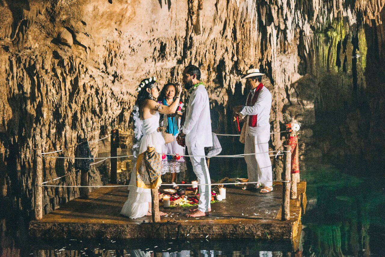 Wedding ceremony on a wooden platform over the water inside a cave