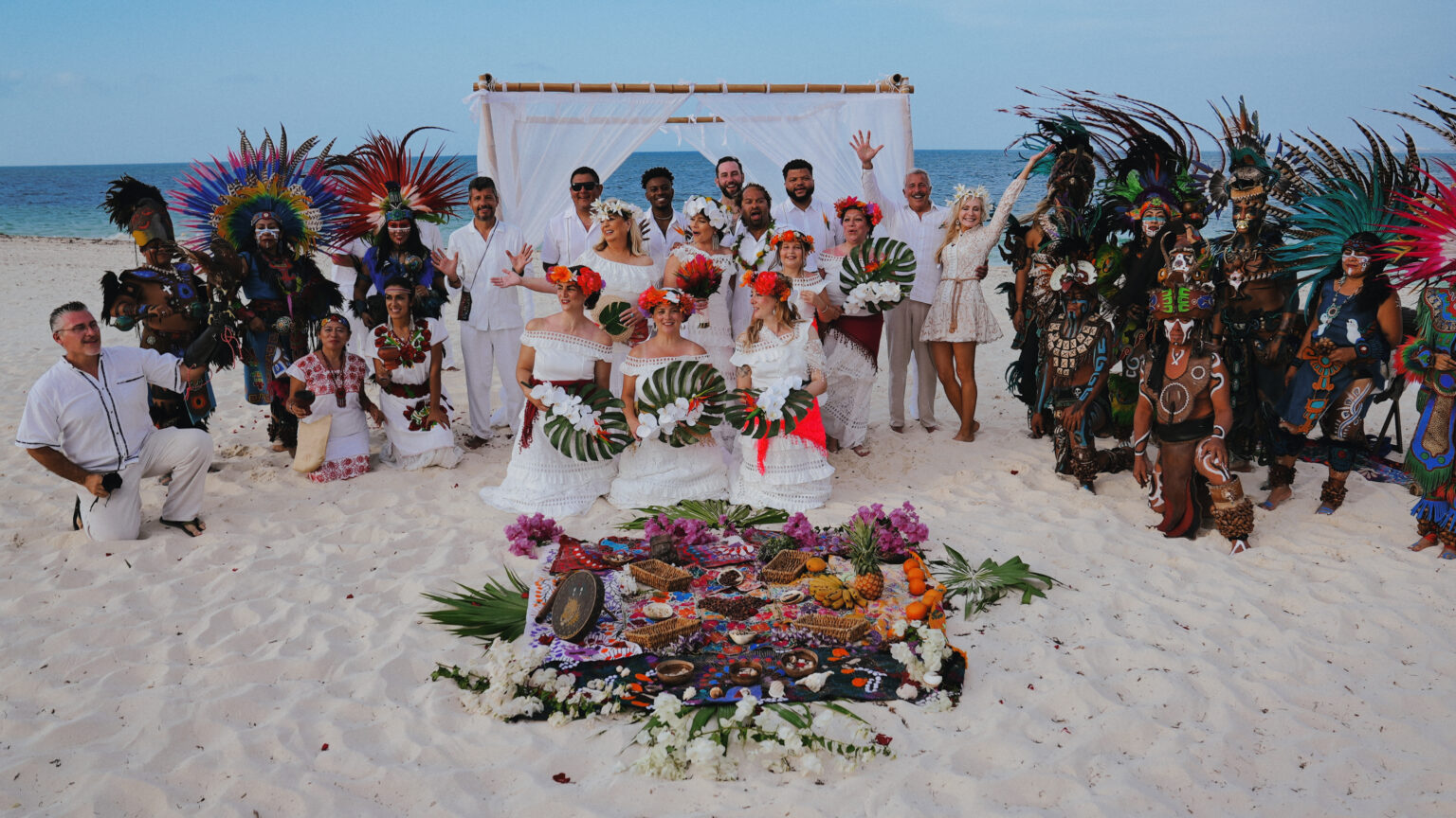Mayan beach ceremony with dancers, the couple and their guests gathered around an offering