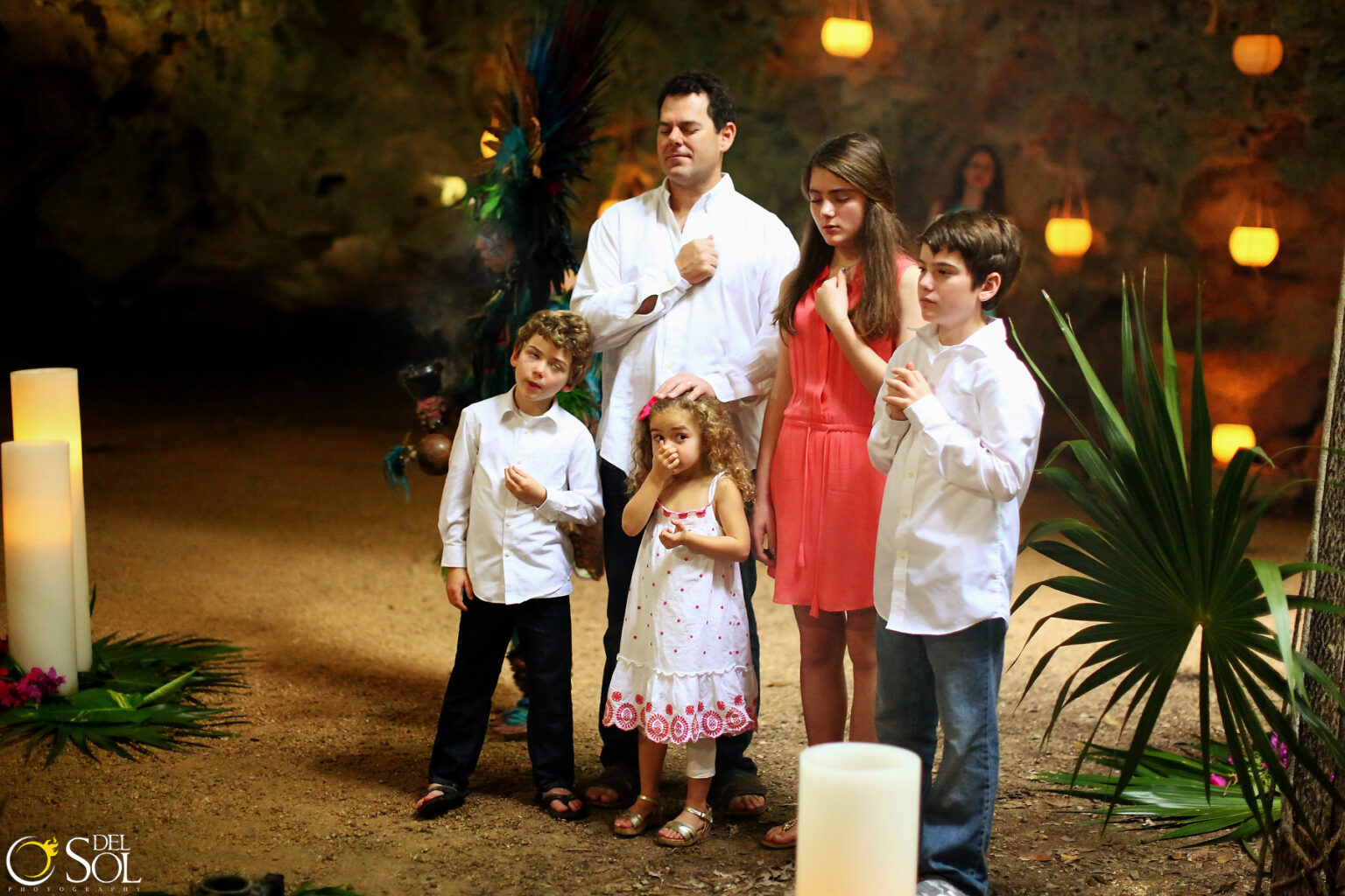 Una familia con sus hijos en una ceremonia maya de aniversario en una cueva iluminada con velas