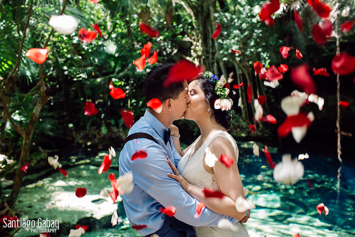 Una pareja se besa en la selva mientras le caen pétalos rojos