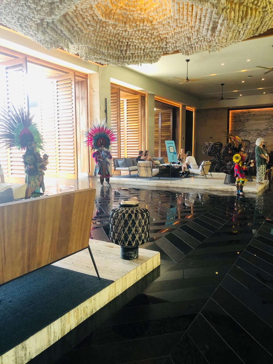 Tres danzantes con penachos de plumas esperando en el lobby de un hotel antes de la bienvenida