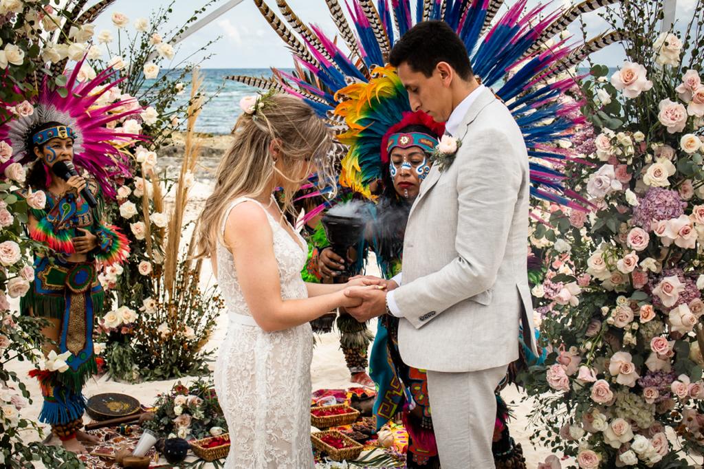 Una pareja intercambia los anillos ante danzantes prehispánicos con penachos de plumas de colores