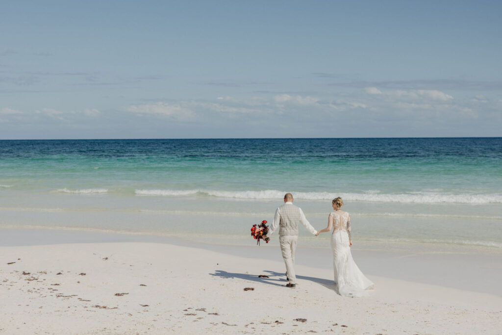 Newlyweds walking along the beach after their spiritual wedding ceremony in Tulum Riviera Maya
