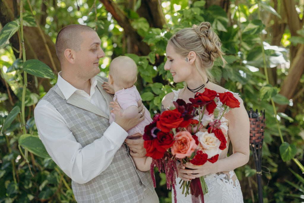 Bride and groom holding their child during intimate spiritual wedding in Tulum Mexico