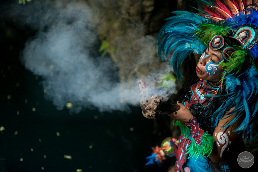 Una sahumadora con penacho de plumas de colores sopla el humo del incienso sagrado