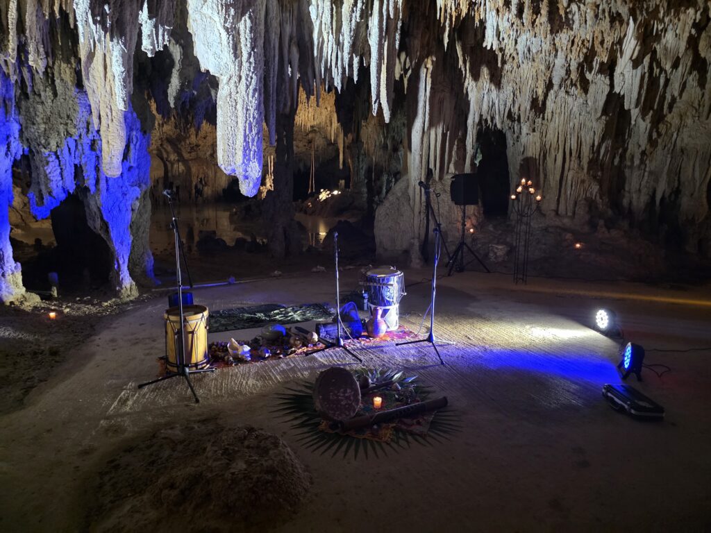 Spiritual ceremony altar prepared inside a cenote cave in Riviera Maya with drums, candles, and sacred elements
