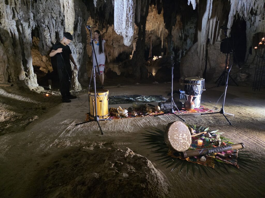 Spiritual officiant performing Mayan-inspired ceremony inside cenote cave in Tulum