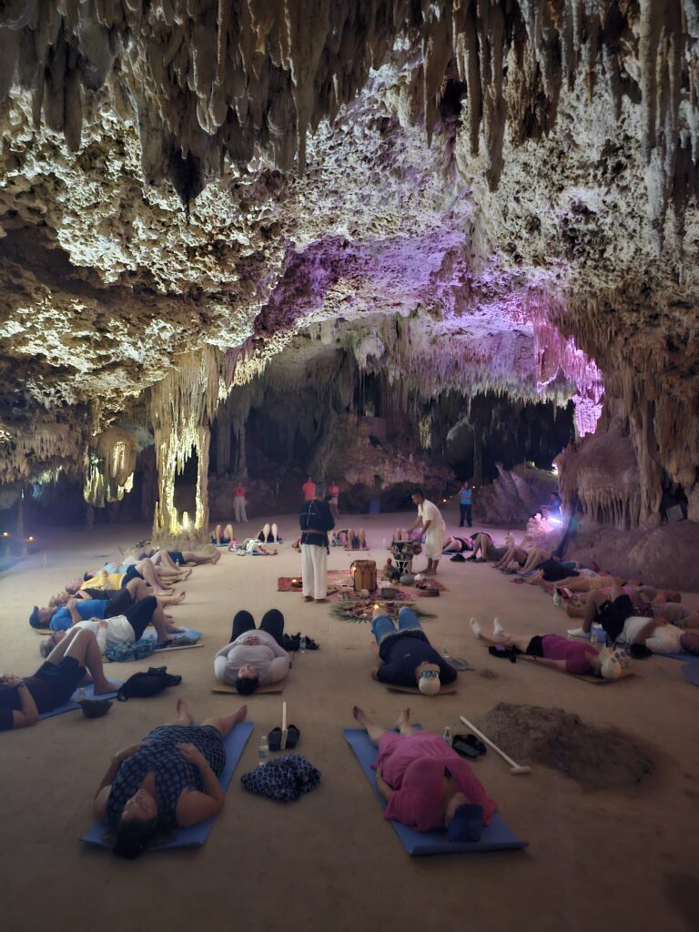 Participants lying on mats during guided spiritual ceremony inside cenote cave in Riviera Maya