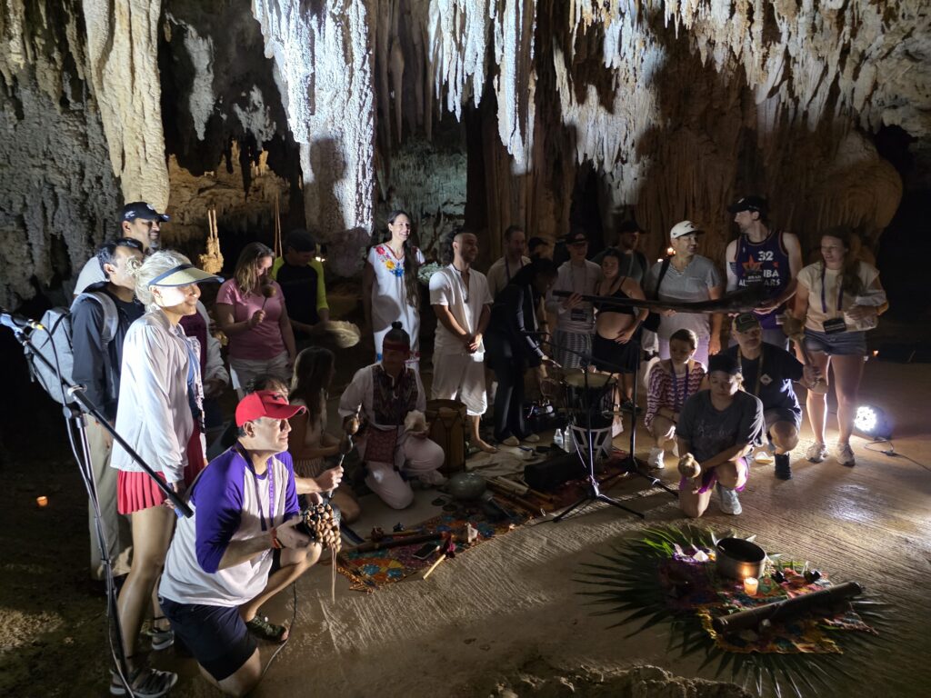 Group gathered around ceremonial altar during spiritual ritual inside cenote cave in Riviera Maya