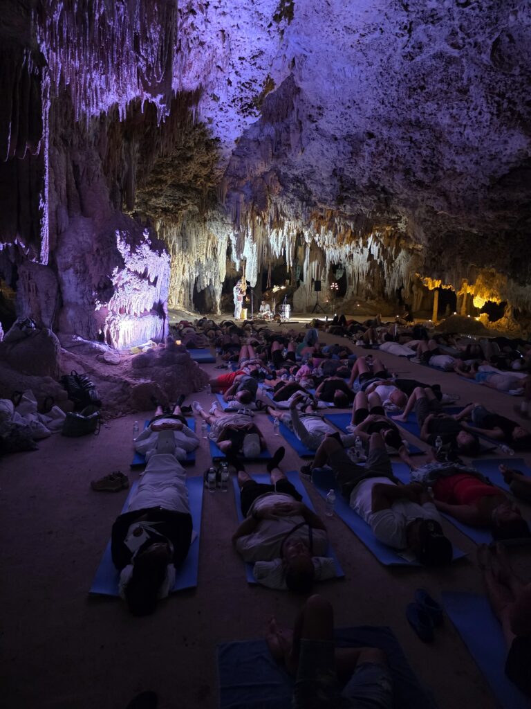 Participants resting on mats during guided spiritual retreat inside illuminated cenote cave in Mexico