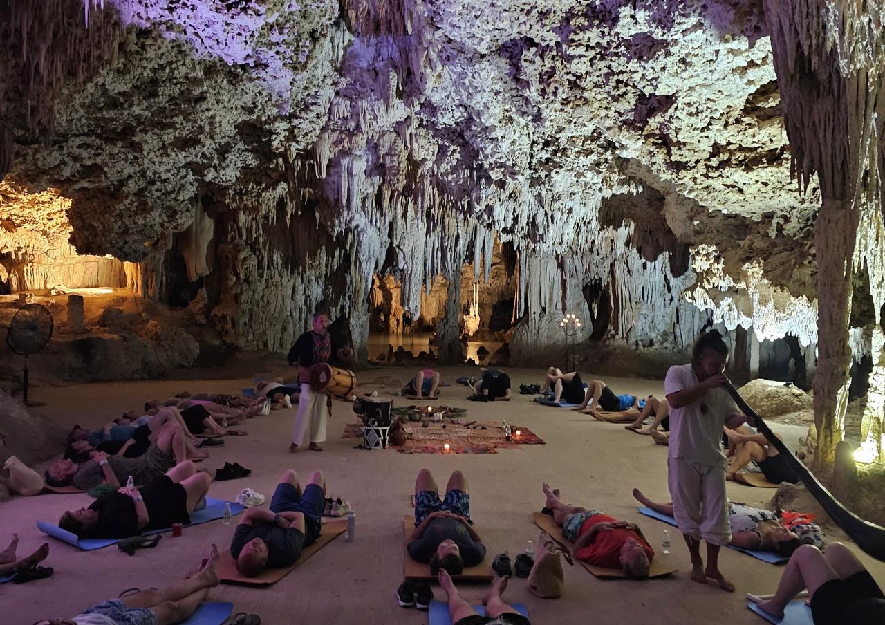 Group lying on mats during a sound healing session inside a cave