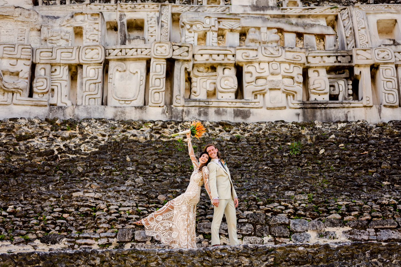 Bride and groom in front of the carved facade of a Mayan temple in Belize