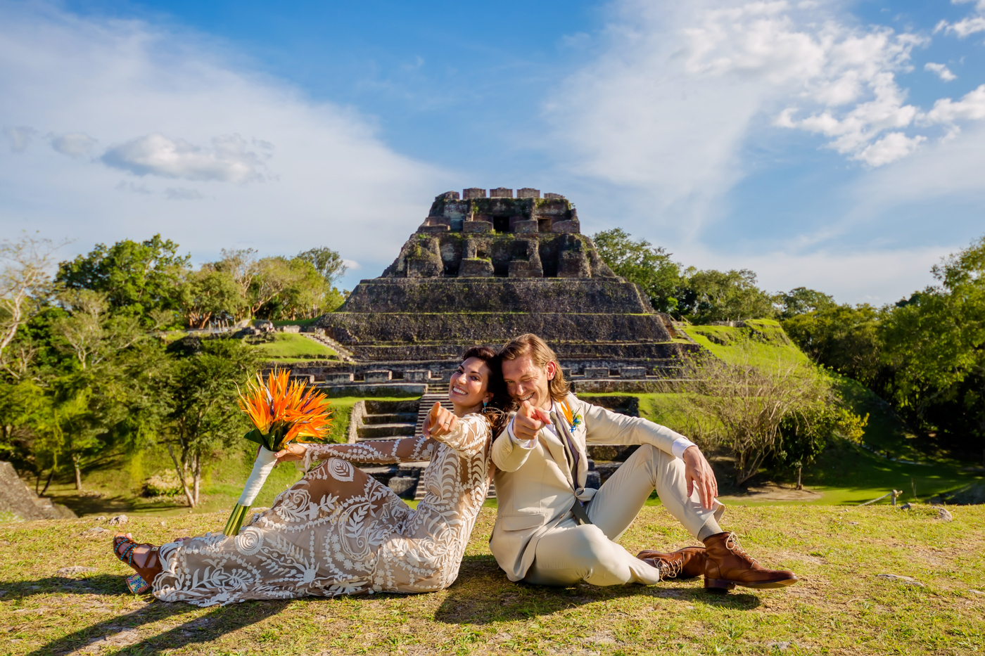 Couple seated on the grass in front of a Mayan pyramid in Belize