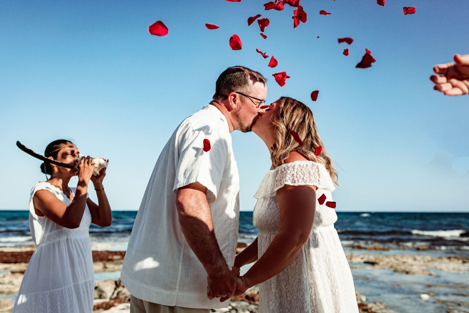 Couple kissing under falling petals on the beach