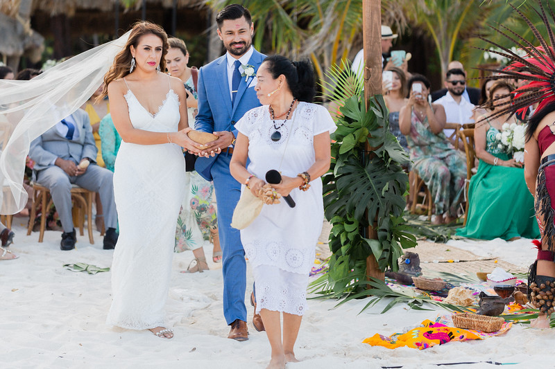 Una guía maya vestida de blanco dirige una ceremonia tradicional para una pareja, con sus invitados alrededor
