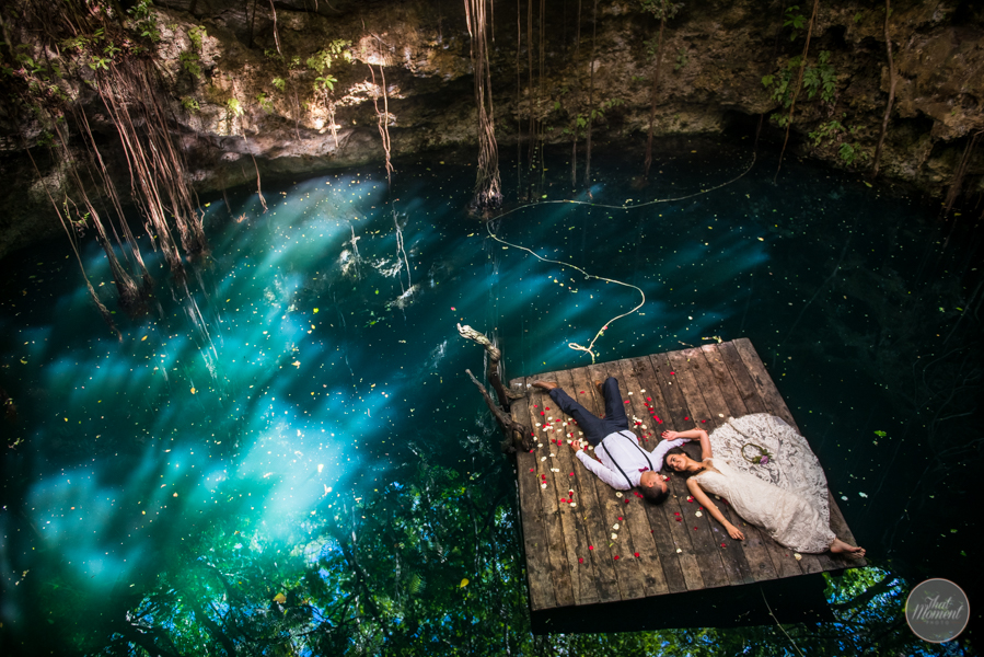 Los novios recostados en una plataforma de madera sobre el agua turquesa de un cenote