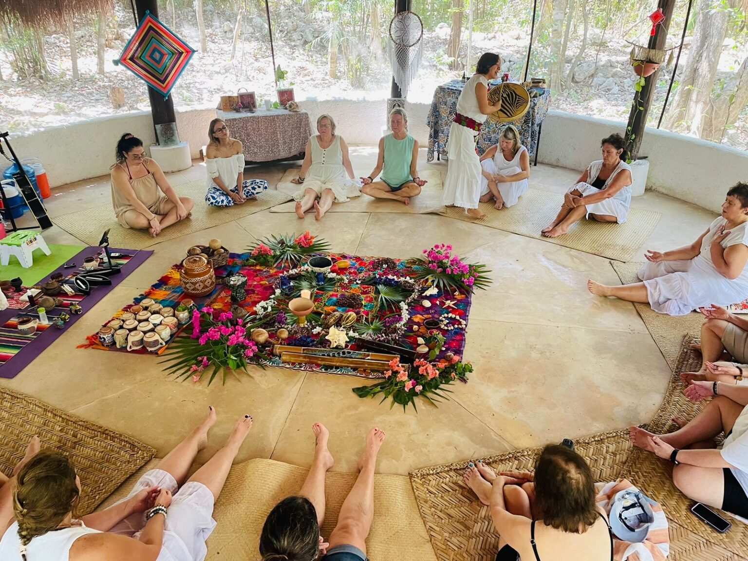 Circle of participants around a flower mandala during a cacao ceremony